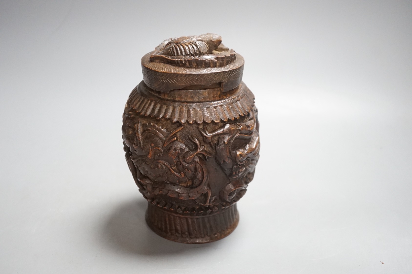 A Burmese carved wooden tobacco jar and cover - 17cm tall